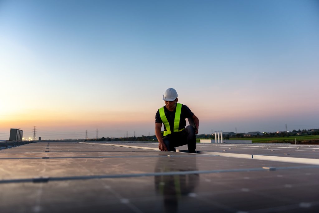 Technician checking Photovoltaic cells panels on factory roof, Maintenance of the solar panels, Engineer service, Inspecor concept. Silhouette Photo.